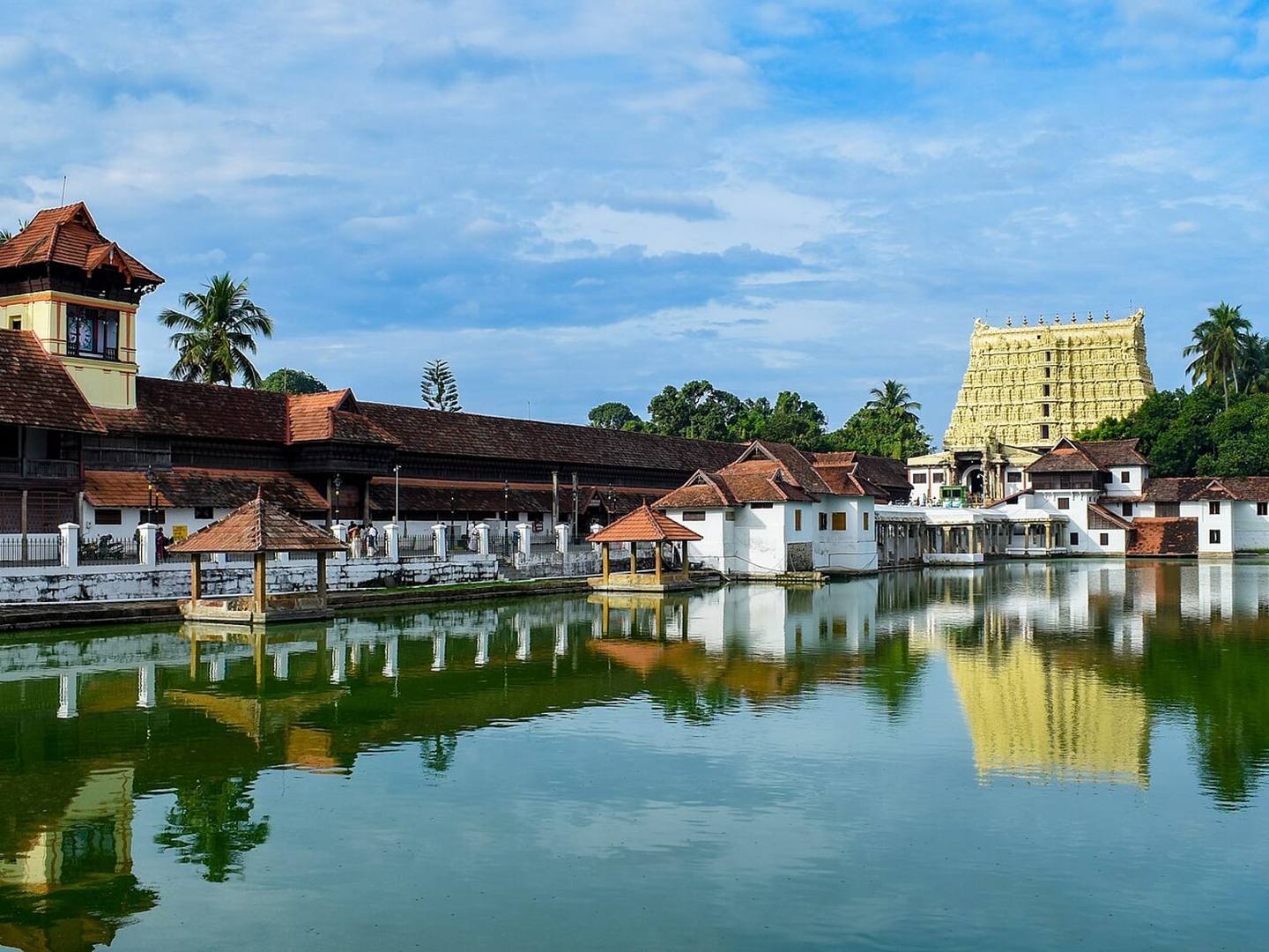 The gopuram of the Sree Padmanabhaswamy Temple reflected in the temple tank, with traditional Kerala buildings alongside