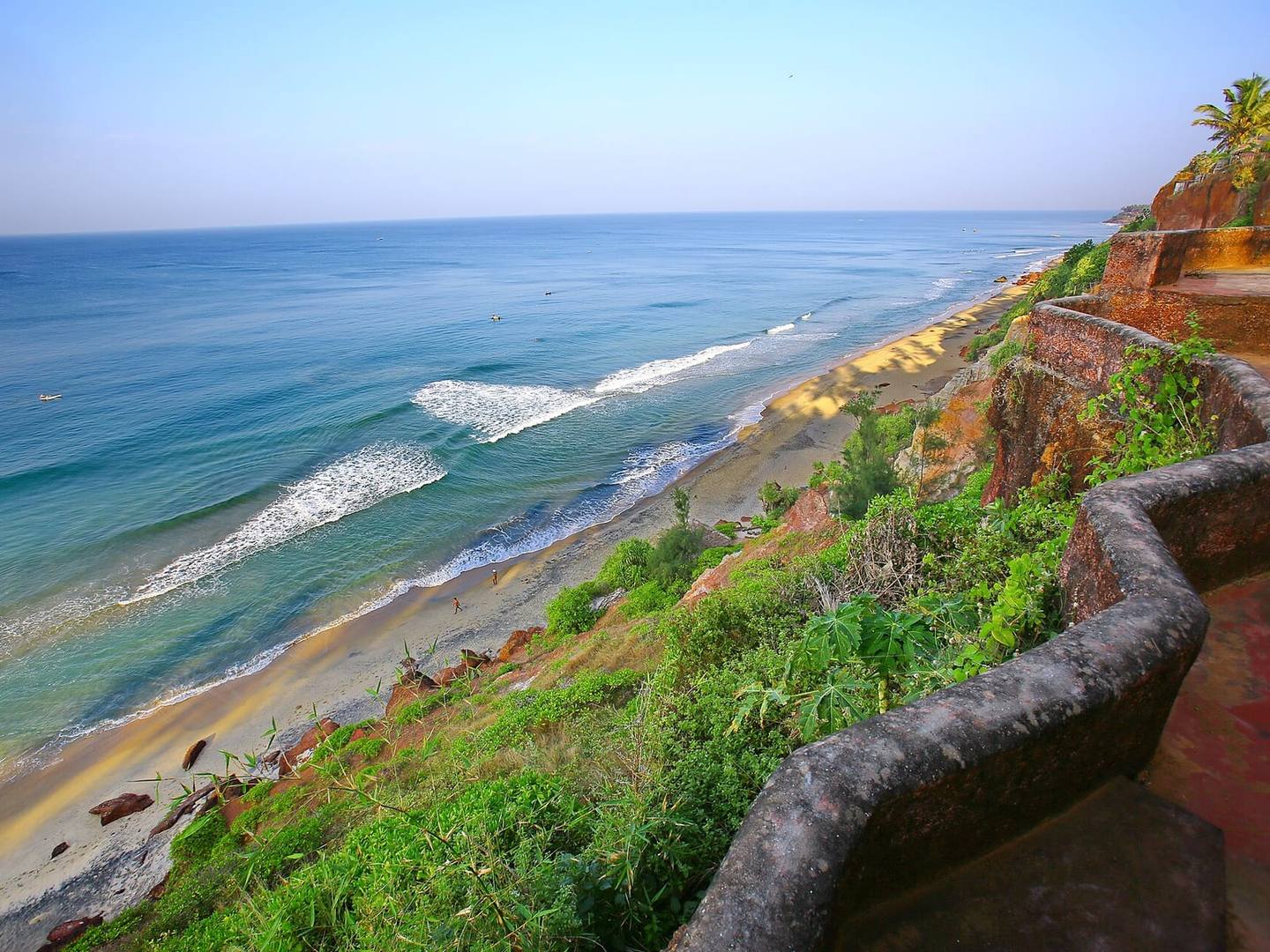 The green clifftop path at Varkala above the beach, with waves rolling in from the Arabian Sea